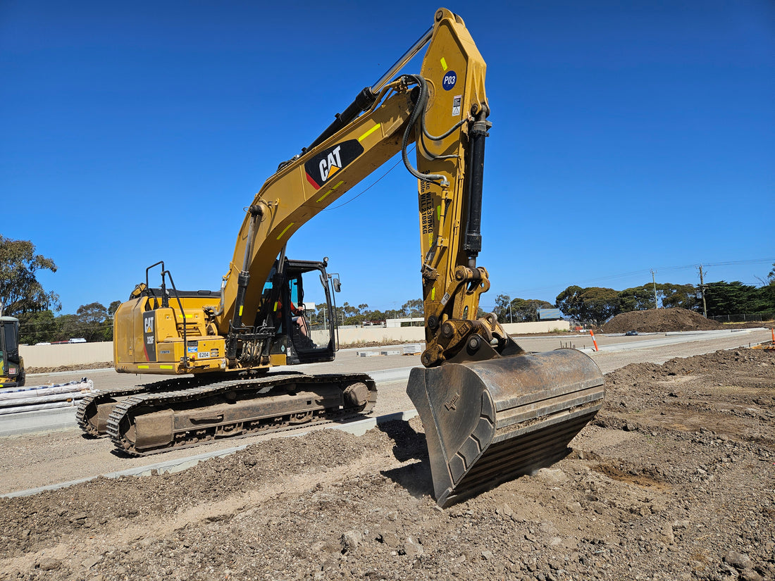 CAT excavator equipped with a heavy-duty bucket from Impact Attachments, performing earthmoving tasks on a construction site.