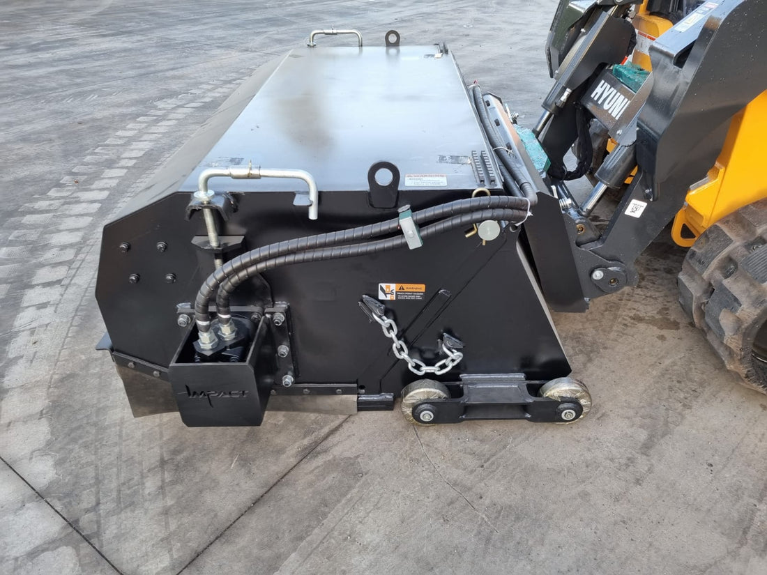Impact Attachments hydraulic broom connected to a Hyundai skid steer, designed for efficient sweeping and debris removal on construction sites.
