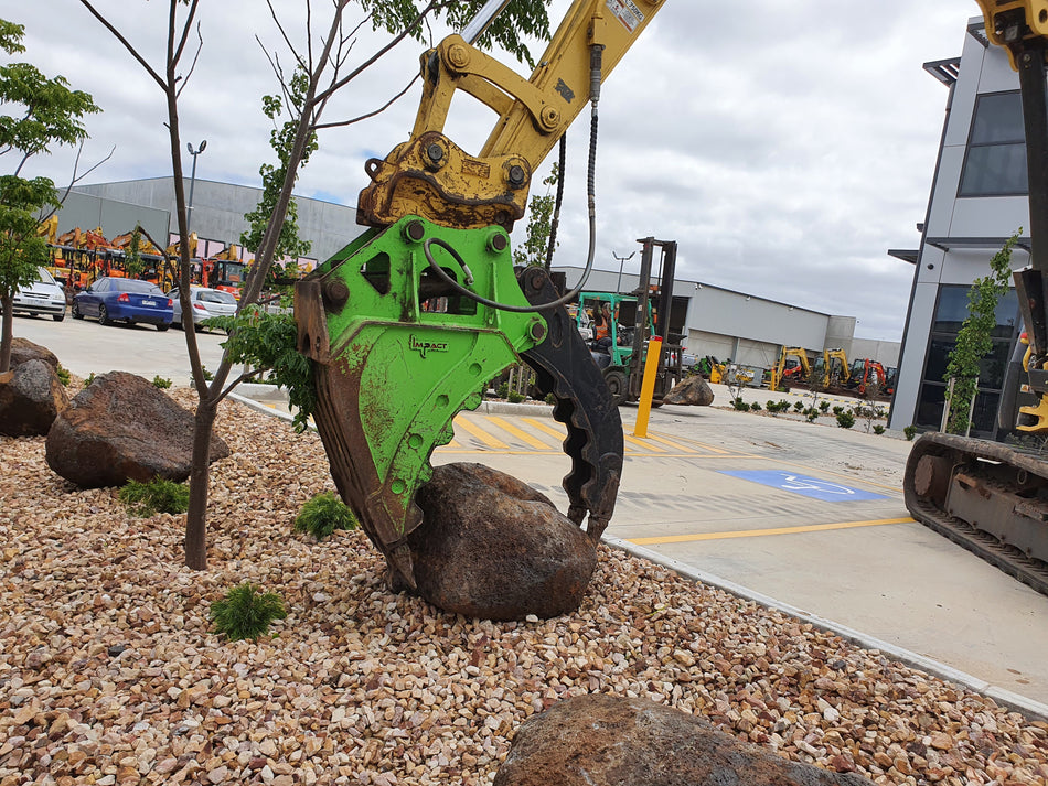 Impact brand grapple bucket attachment in action, gripping a large rock, showcasing its durability and precision for material handling tasks. Ideal for construction, landscaping, and excavation projects, this heavy-duty attachment enhances the efficiency and versatility of excavators, allowing operators to manage challenging terrains and heavy loads with ease.
