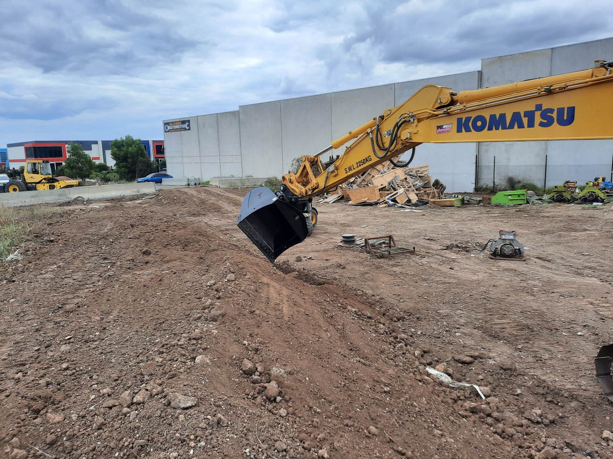 Komatsu excavator equipped with an Impact 4-in-1 bucket performing earthmoving operations on a construction site. The image highlights the versatility of the Impact 4-in-1 bucket attachment, ideal for digging, grading, and material handling in construction projects. Perfect for contractors looking for efficient and reliable excavator attachments compatible with Komatsu machinery.