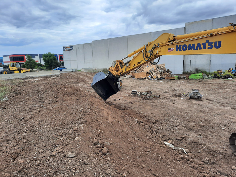Komatsu excavator equipped with an Impact 4-in-1 bucket performing earthmoving operations on a construction site. The image highlights the versatility of the Impact 4-in-1 bucket attachment, ideal for digging, grading, and material handling in construction projects. Perfect for contractors looking for efficient and reliable excavator attachments compatible with Komatsu machinery.