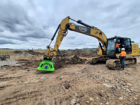 Caterpillar excavator operated by Tweed Civil, equipped with an Impact hydraulic compaction plate, used for efficient soil compaction in large-scale earthmoving projects. This combination ensures optimal ground preparation and site stabilization