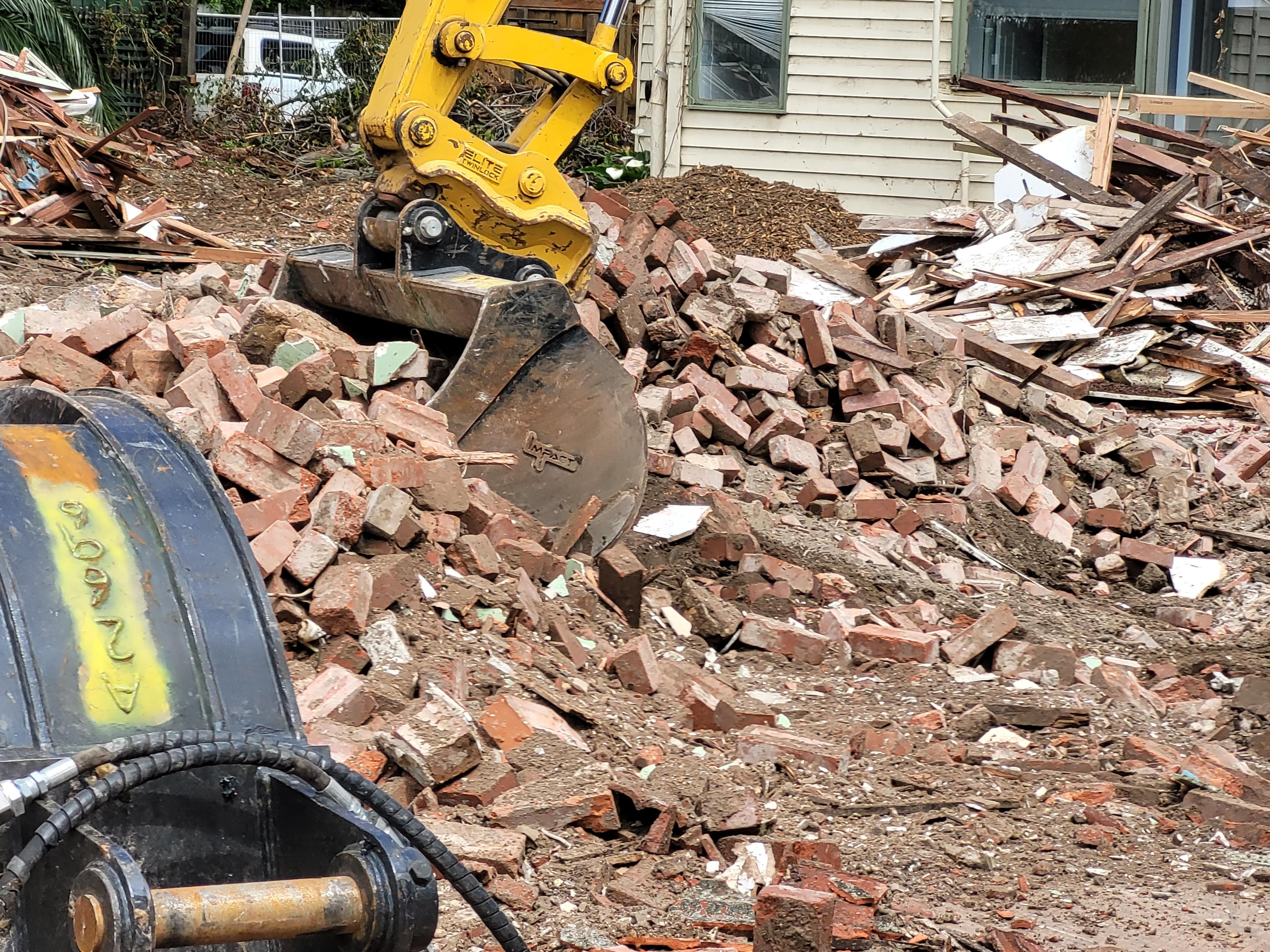 Impact Attachments excavator bucket used for clearing and handling brick debris during a demolition project.