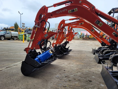 Row of Kubota mini excavators equipped with hydraulic thumbs and buckets, lined up in an industrial yard, ready for deployment in various construction, excavation, and landscaping projects. The hydraulic thumbs enhance material handling capabilities, making these machines ideal for precision work in tight spaces. Kubota mini excavators are known for their reliability, efficiency, and versatility on job sites