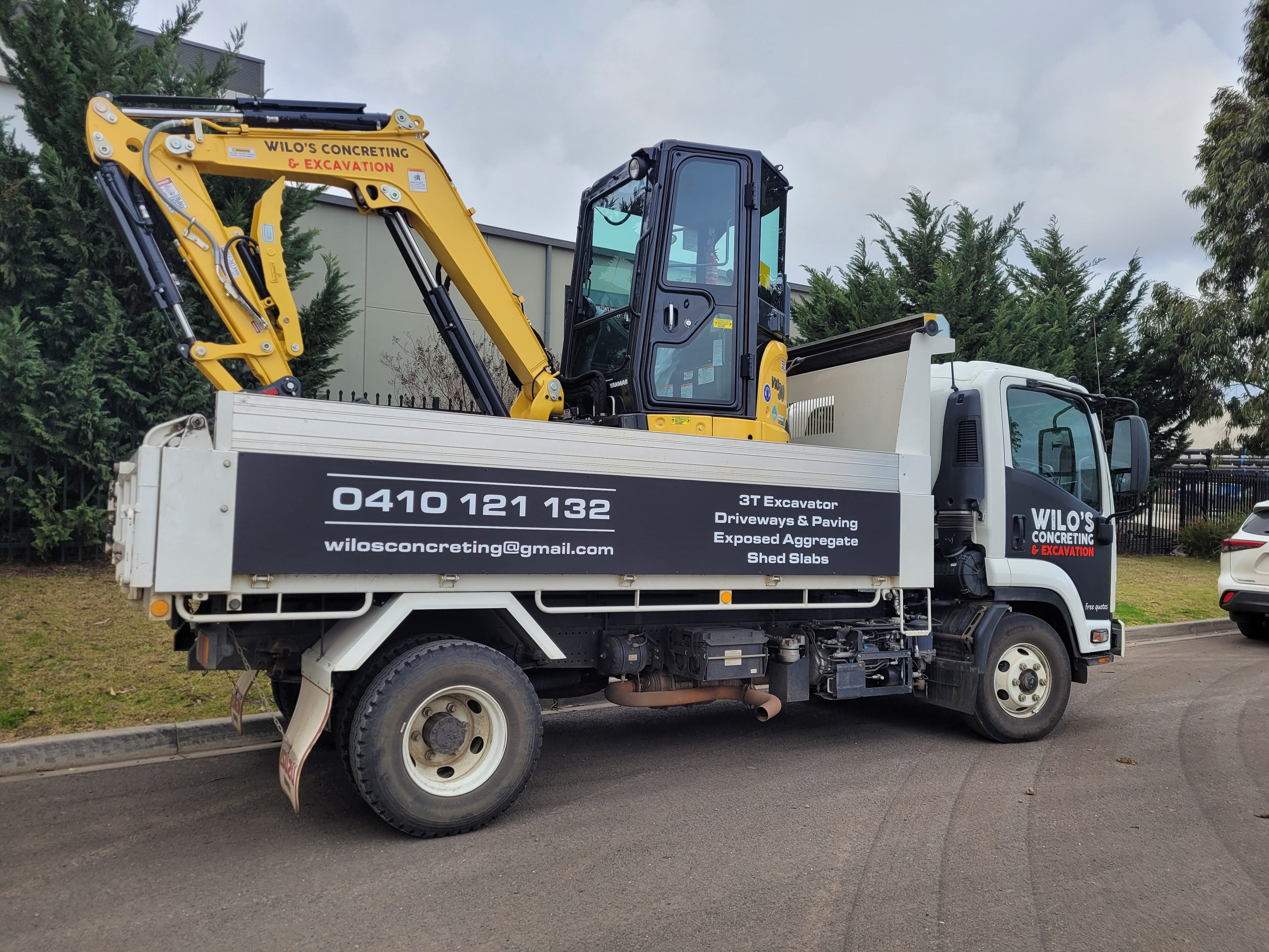 Wilo’s Concreting & Excavation truck carrying a 3-tonne excavator, showcasing professional concrete services including driveways, paving, exposed aggregate, and shed slabs, with contact details prominently displayed.