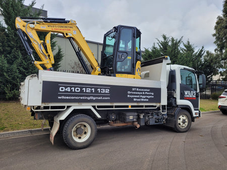 Wilo’s Concreting & Excavation truck carrying a 3-tonne excavator, showcasing professional concrete services including driveways, paving, exposed aggregate, and shed slabs, with contact details prominently displayed.