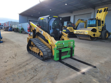 CAT 279D skid steer loader equipped with Impact Attachments pallet forks, designed for efficient material handling and transport on construction sites.