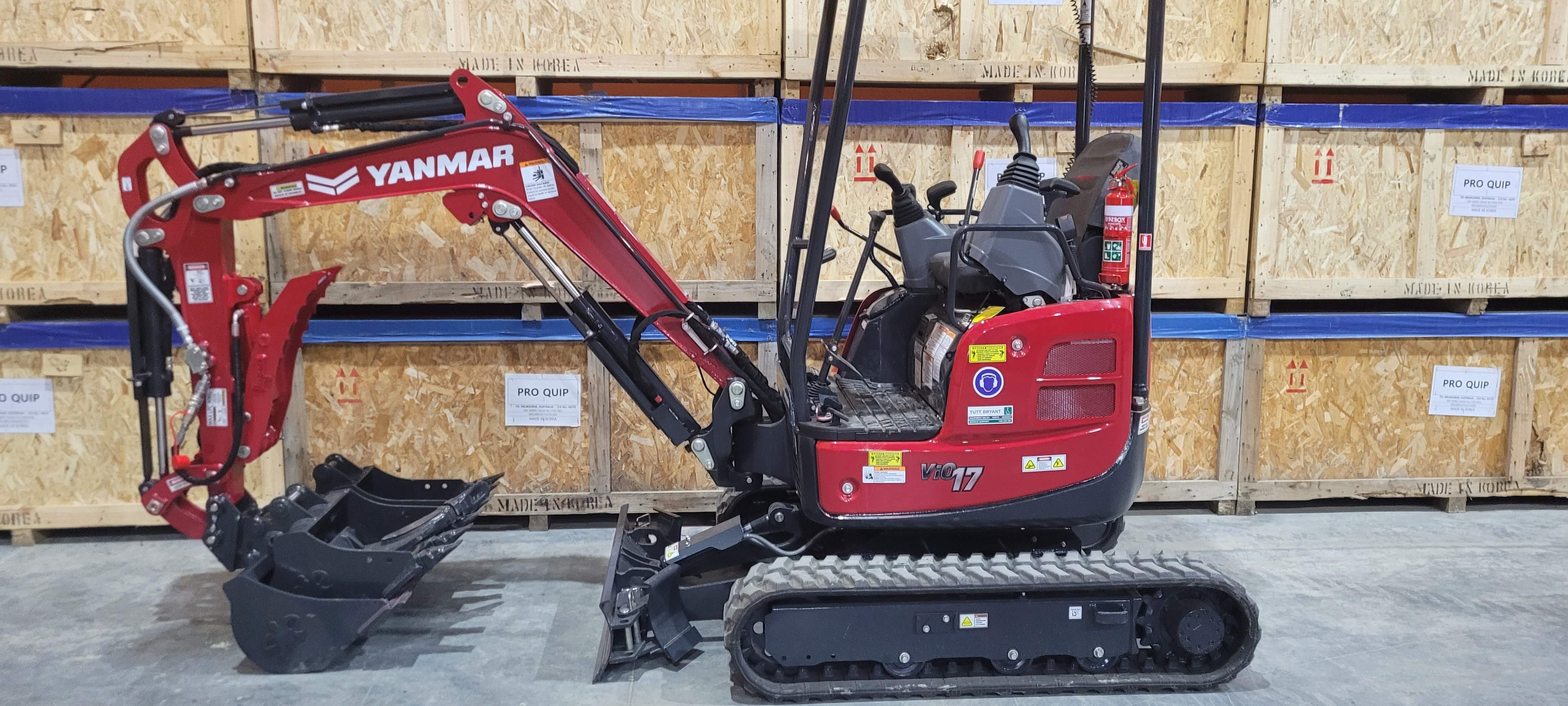 Yanmar ViO17 mini excavator equipped with a hydraulic thumb attachment and three buckets, displayed in a warehouse setting. Ideal for precision digging and material handling in confined spaces. The mini excavator is compact and versatile, making it suitable for construction, landscaping, and excavation projects. This setup enhances efficiency in moving and manipulating various materials on job sites.