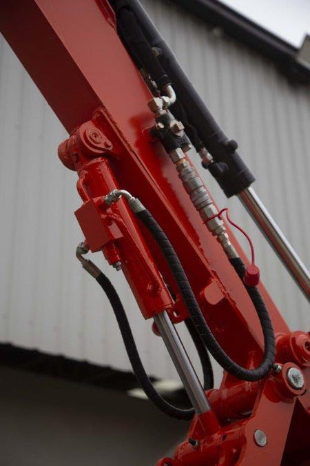 Close-up of an Impact Attachments hydraulic thumb in bright red, mounted on an excavator arm. The hydraulic thumb features a serrated edge designed for gripping and handling materials efficiently. The attachment is equipped with high-quality hydraulic fittings and hoses for optimal performance. Ideal for excavation and material handling tasks, this heavy-duty attachment showcases the durability and precision engineering of Impact Attachments.

