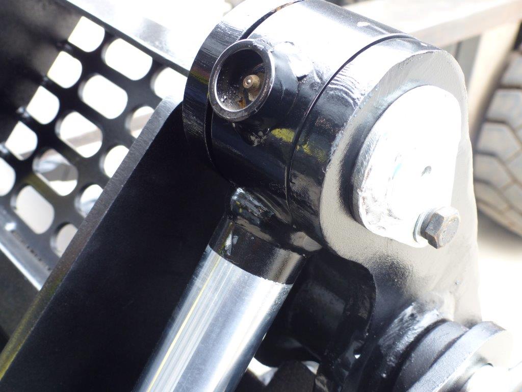 Close-up view of an Impact 4 in 1 bucket attachment on a track loader/skid steer, highlighting the heavy-duty construction and branding, ideal for various excavation and material handling tasks in construction.