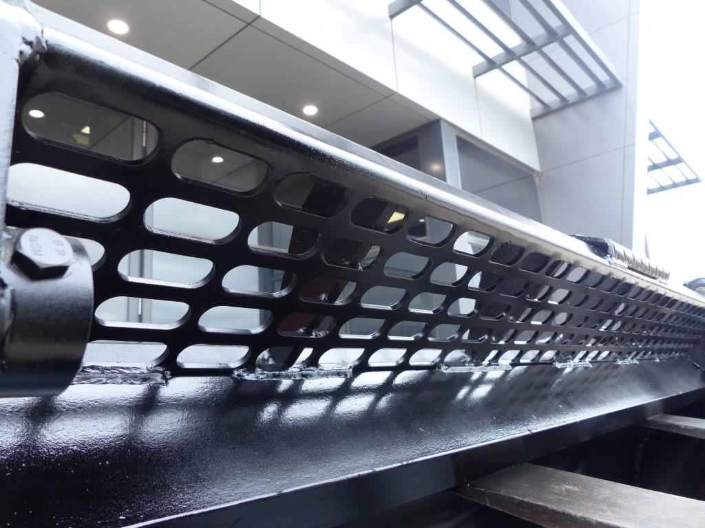 Close-up view of an Impact 4 in 1 bucket attachment on a track loader/skid steer, highlighting the heavy-duty construction and branding, ideal for various excavation and material handling tasks in construction.