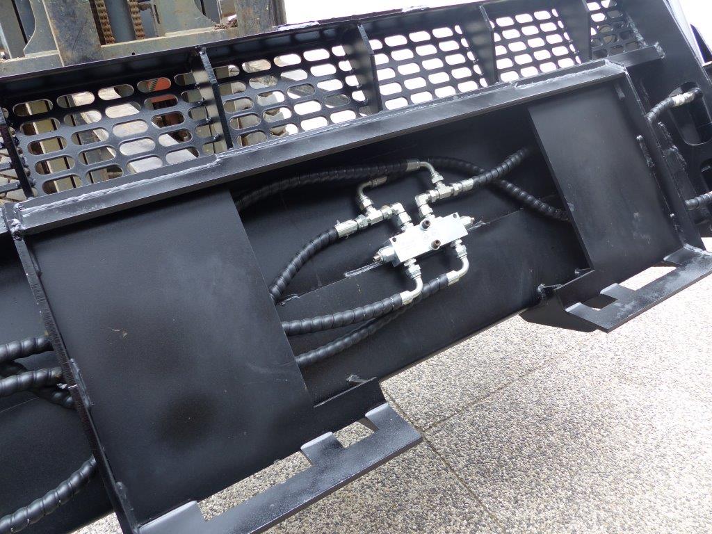 Close-up view of an Impact 4 in 1 bucket attachment on a track loader/skid steer, highlighting the heavy-duty construction and branding, ideal for various excavation and material handling tasks in construction.