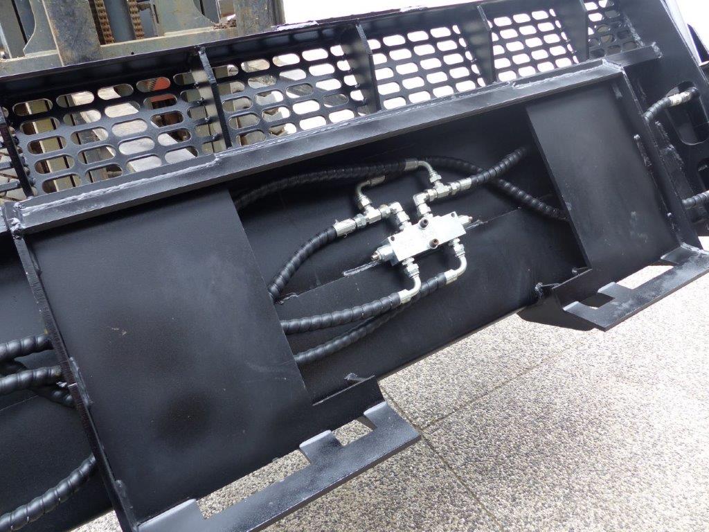 Close-up view of an Impact 4 in 1 bucket attachment on a track loader/skid steer, highlighting the heavy-duty construction and branding, ideal for various excavation and material handling tasks in construction.
