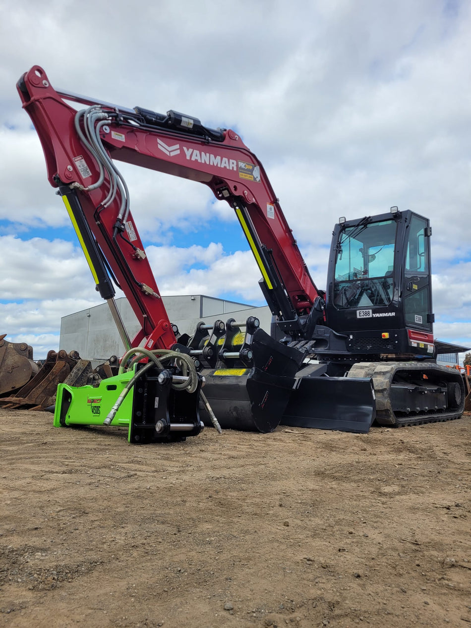 An image of a red Yanmar excavator equipped with a green hydraulic breaker attachment, positioned on a construction site with a cloudy sky in the background. The excavator is ready for heavy-duty work, showcasing the durability and functionality of the hydraulic breaker attachment