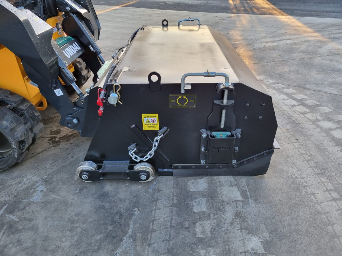 Impact Attachments hydraulic broom connected to a Hyundai skid steer, optimized for heavy-duty sweeping tasks on industrial and construction sites.